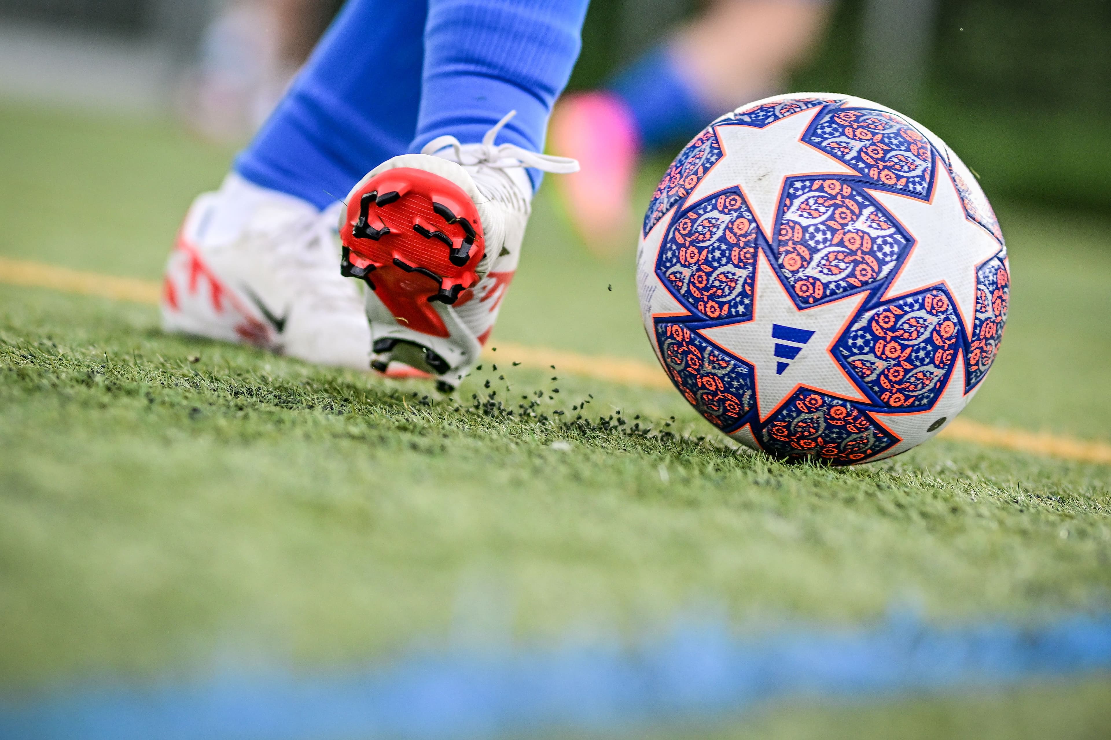 Grossaufnahme der Schuhe einer Fussballerin, die einen Ball spielt. 